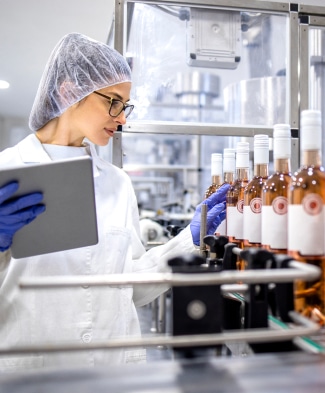 Femme travaillant dans un entrepôt en train d'examiner une ligne de production de bouteilles de vin